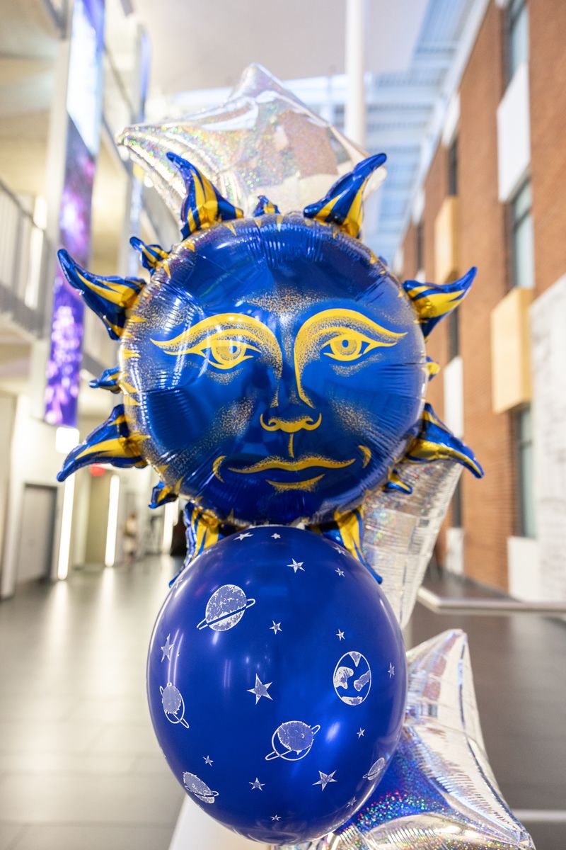 A blue and gold sun balloon above a planet print balloon and silver star balloons in the atrium